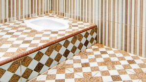 A bathroom with a checkered floor, a white bathtub, and striped walls.