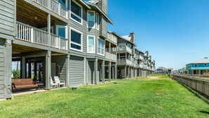 A row of townhouses with balconies, a grassy lawn, and a wooden fence.