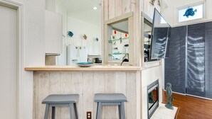 A kitchen with wooden accents, a bar area with stools, a fish decoration, and a fish-themed artwork on the wall.
