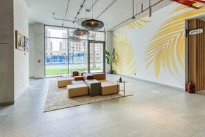 A spacious lobby with a large seating area, a wall mural, and a view of the outside.
