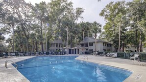 Une piscine avec des chaises longues et un bâtiment en arrière-plan.