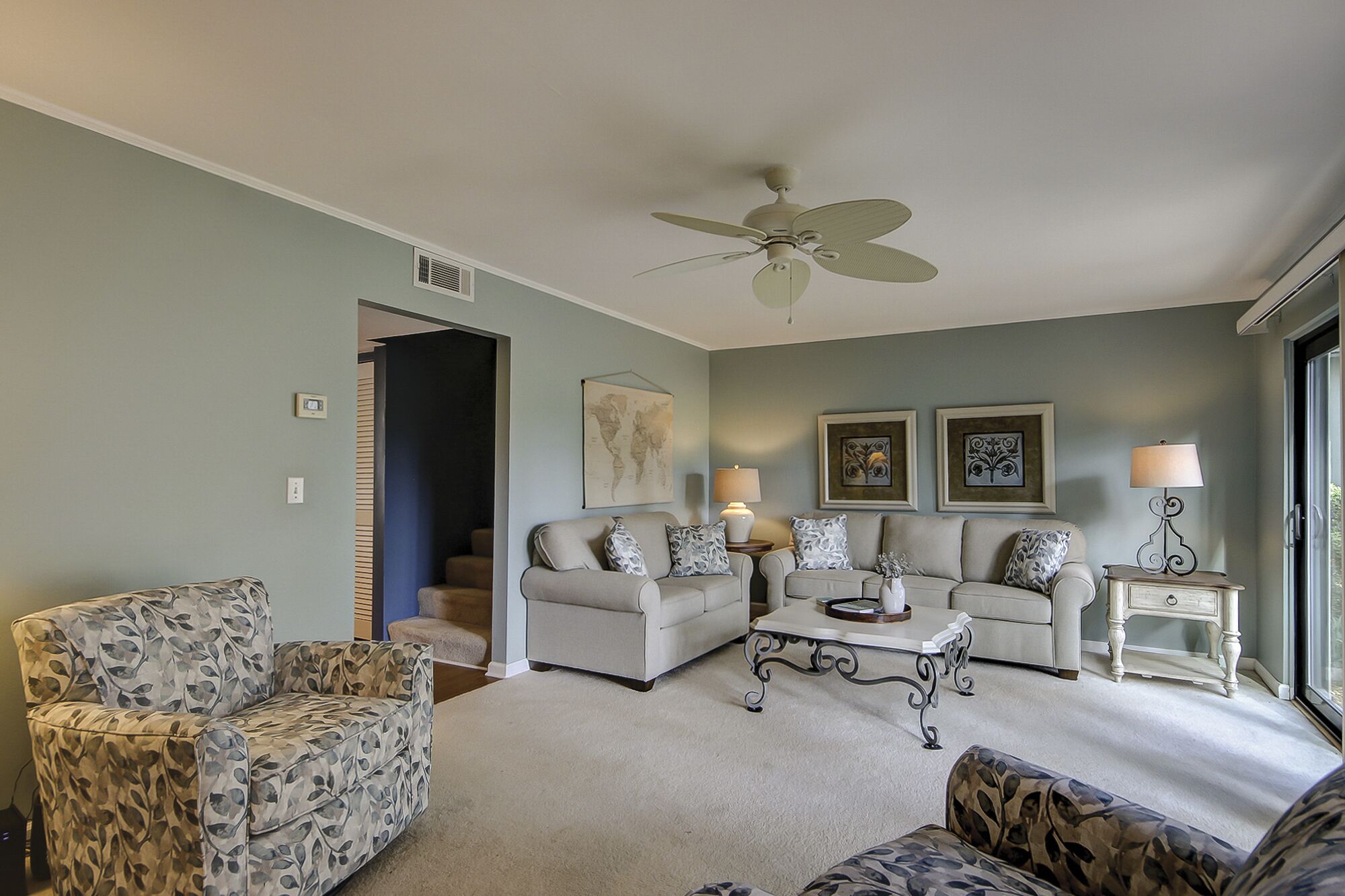 A living room with a ceiling fan, two sofas, a coffee table, and a side table with lamps.
