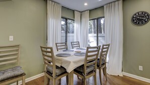 Un coin repas avec une table ronde, six chaises et une horloge au mur.