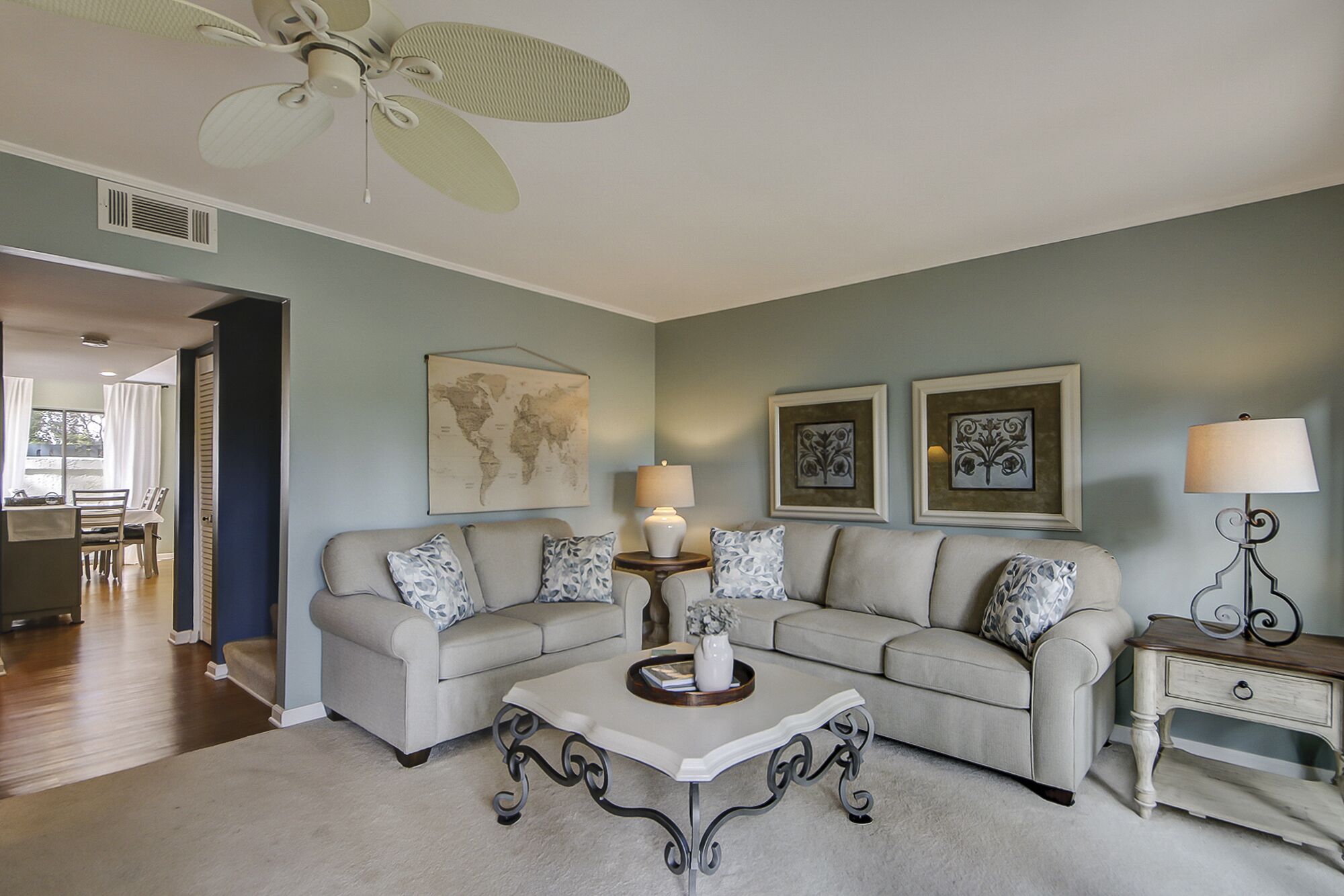 A living room with a beige sofa, a coffee table, and a world map on the wall.