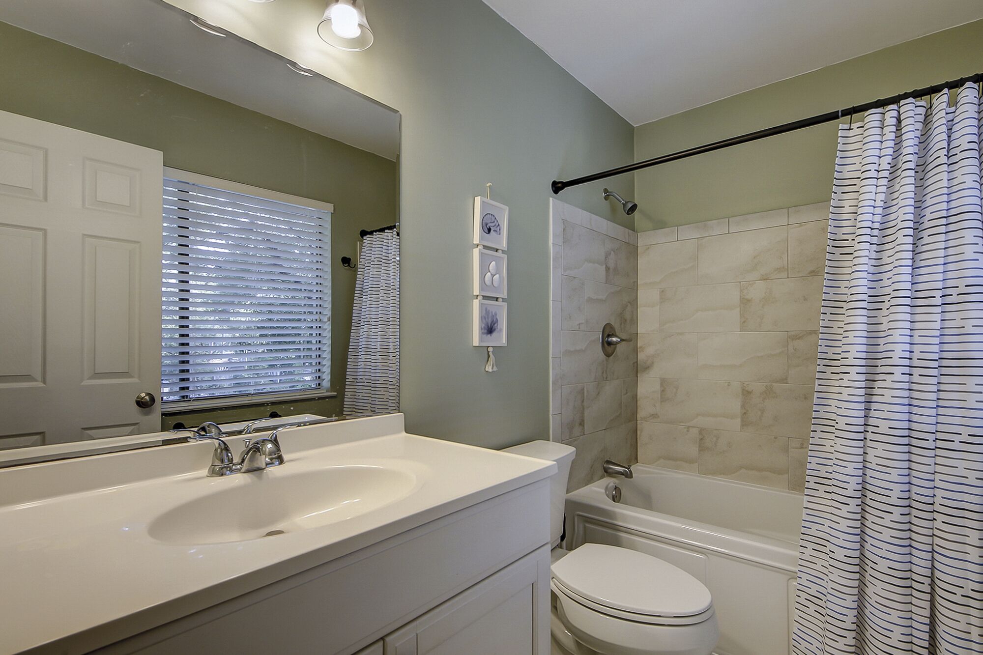 A bathroom with a white sink, a toilet, and a shower with a striped curtain.