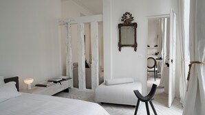 Un dormitorio con cama, mesita de noche, lámpara y una silla.