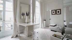 Una sala de estar moderna con un sofá blanco, una mesa de comedor y un ventanal con cortinas.