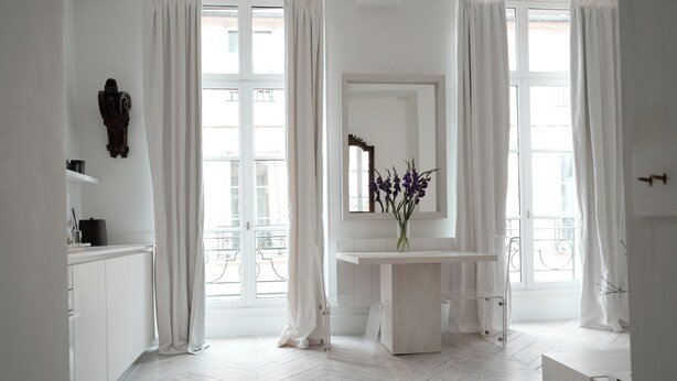 Un baño moderno con un tocador blanco, un espejo y un florero con flores moradas.