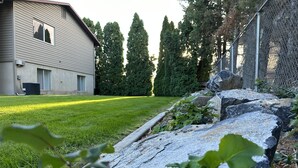 Un barrio residencial con un césped cuidado, un muro de piedra y una valla de alambre.
