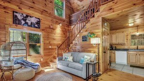 L’intérieur d’une cabane en bois comprend un escalier, un canapé, une table à manger et un coin cuisine.
