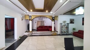 Un salón amplio con un sofá rojo, una vitrina de vidrio y piso de baldosas.