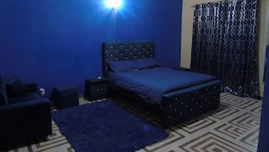 Un dormitorio con cama, mesitas de noche, alfombra y suelo estampado.