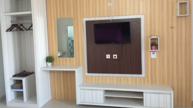 Un salon moderne avec un téléviseur encastré, une petite étagère et un miroir.