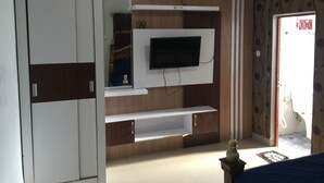 Une chambre avec une armoire, un téléviseur fixé au mur et un lit.