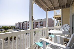 Enjoy the ocean view from this balcony with a table and two chairs.
