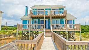 A two-story beachfront house with a wooden deck and a staircase leading to the entrance. - Irish Mist, Oceanfront House in Emerald Isle, NC! (Emerald Isle)
