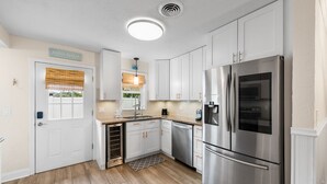 Una cocina moderna con armarios blancos, electrodomésticos de acero inoxidable y piso de madera.