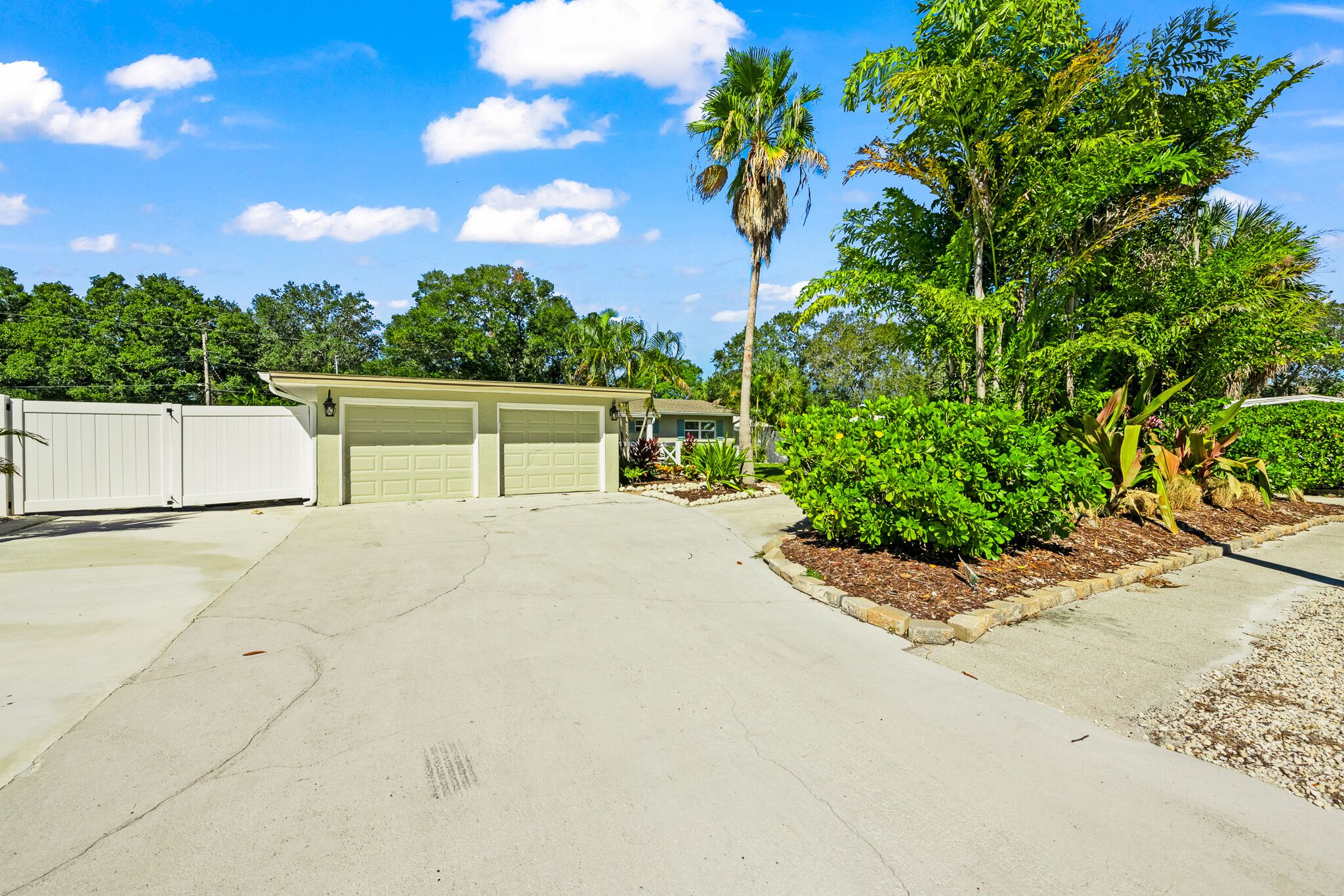A two-car garage attached to a house with a well-maintained lawn and a palm tree.