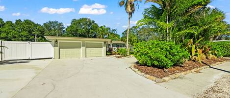 A two-car garage attached to a house with a well-maintained lawn and a palm tree.