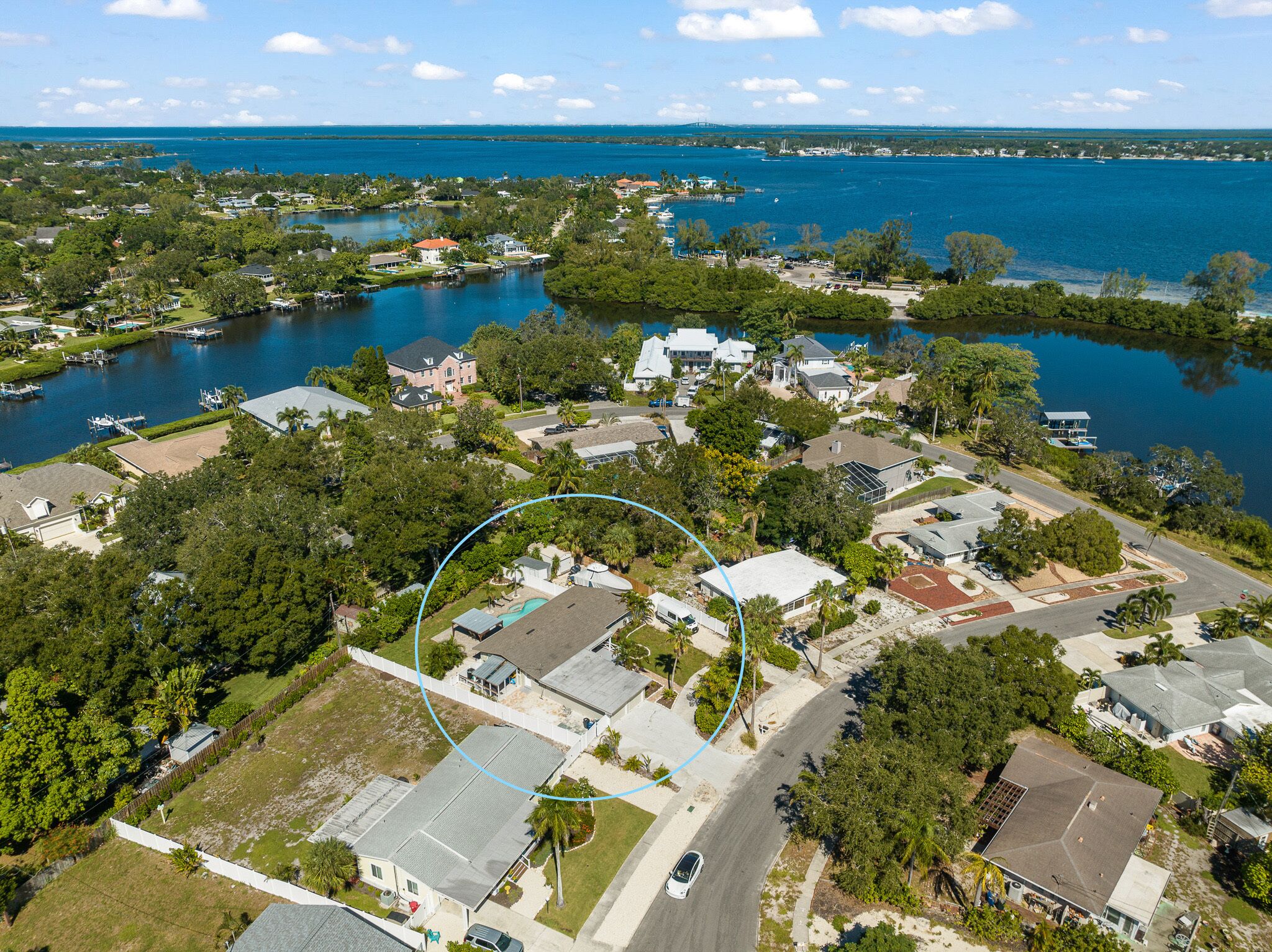 An aerial view of a residential area with houses, a road, and a body of water.