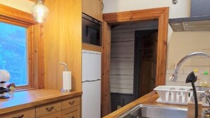 Een keuken met houten kastjes, een roestvrijstalen spoelbak en een raam.