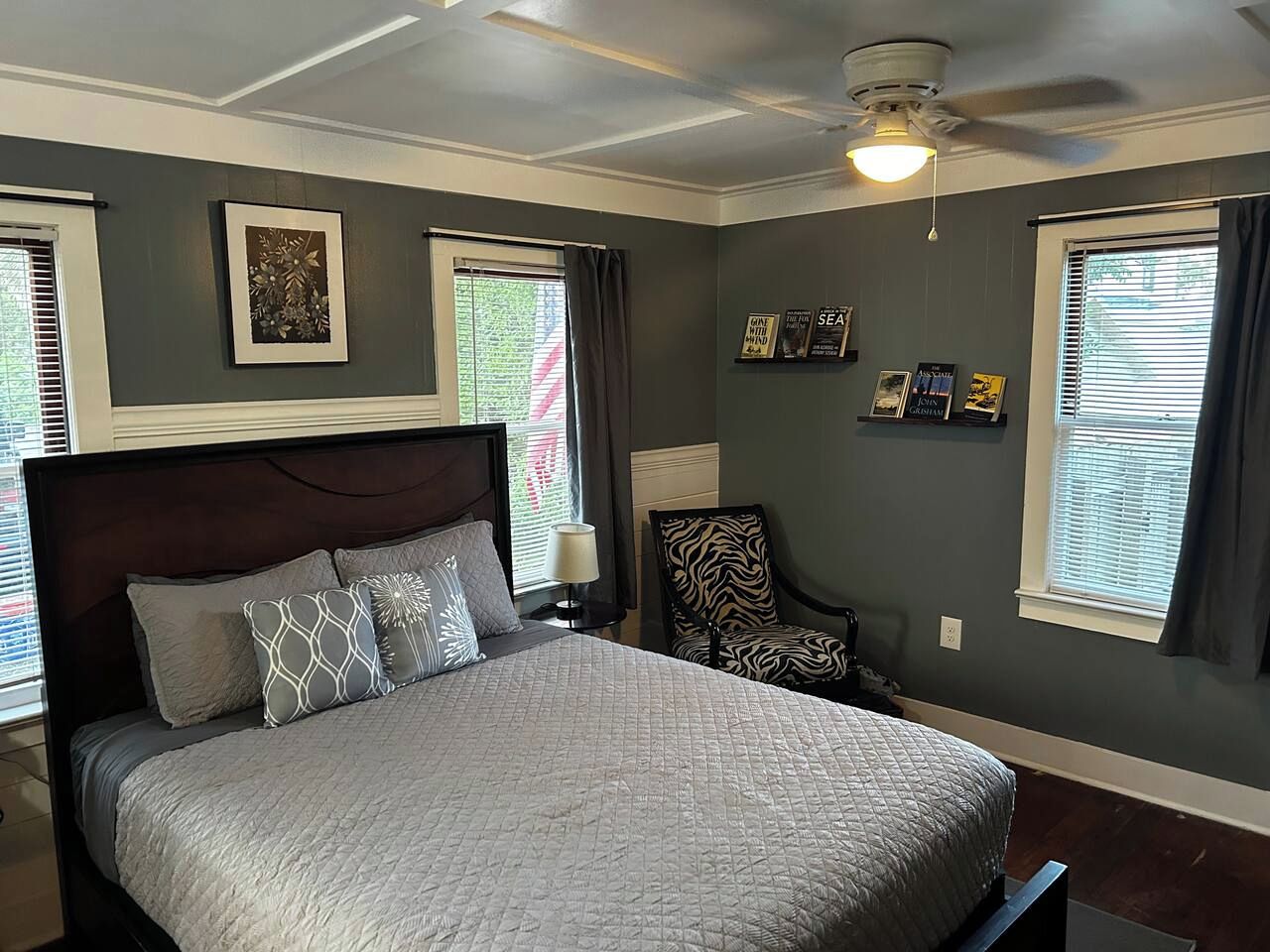 Ein Schlafzimmer mit einem großen Bett, einem Sessel, einem Deckenventilator und Kunstwerken an den Wänden.