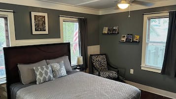 Ein Schlafzimmer mit einem großen Bett, einem Sessel, einem Deckenventilator und Kunstwerken an den Wänden.