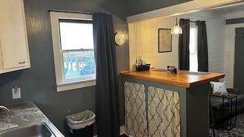 A compact kitchen with a wooden countertop, a sink, and a window with curtains.