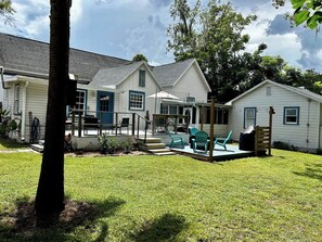 A residential property with a covered patio, outdoor seating, and a well-maintained lawn. - Cute cottage-historic district-hot tub (Ocala)