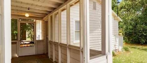 A covered porch with a wooden ceiling and a view of a house.