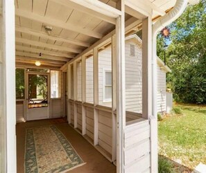 A covered porch with a wooden ceiling and a view of a house. - Cute cottage-historic district-hot tub (Ocala)