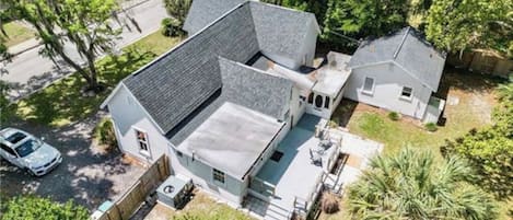A two-story house with a sloped roof, a fenced yard, and a palm tree.