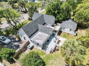 A two-story house with a sloped roof, a fenced yard, and a palm tree. - Cute cottage-historic district-hot tub (Ocala)