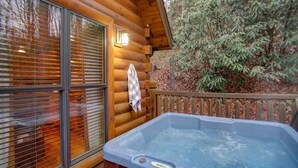 A wooden cabin with a hot tub on the deck.