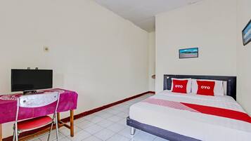 A bedroom with a bed, a TV on a desk, and a small picture on the wall.