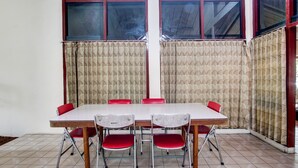 Una sala de conferencias con una mesa rectangular, sillas rojas y cortinas estampadas.