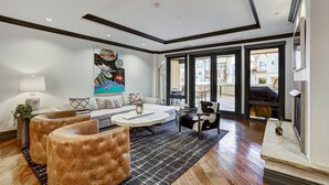 A modern living room with a sofa, ottomans, a coffee table, and a large painting.