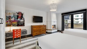A modern hotel room with a large bed, a flat-screen TV, a wooden dresser, and a painting on the wall.