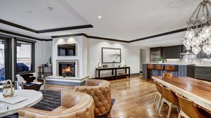 A modern living room with a fireplace, leather seating, a dining area, and a kitchen with bar seating.