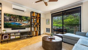 A spacious living room with a large flat-screen TV, a wooden coffee table, and a comfortable sofa. - Grand Champions 29 1 Bedroom Condo (Kihei)
