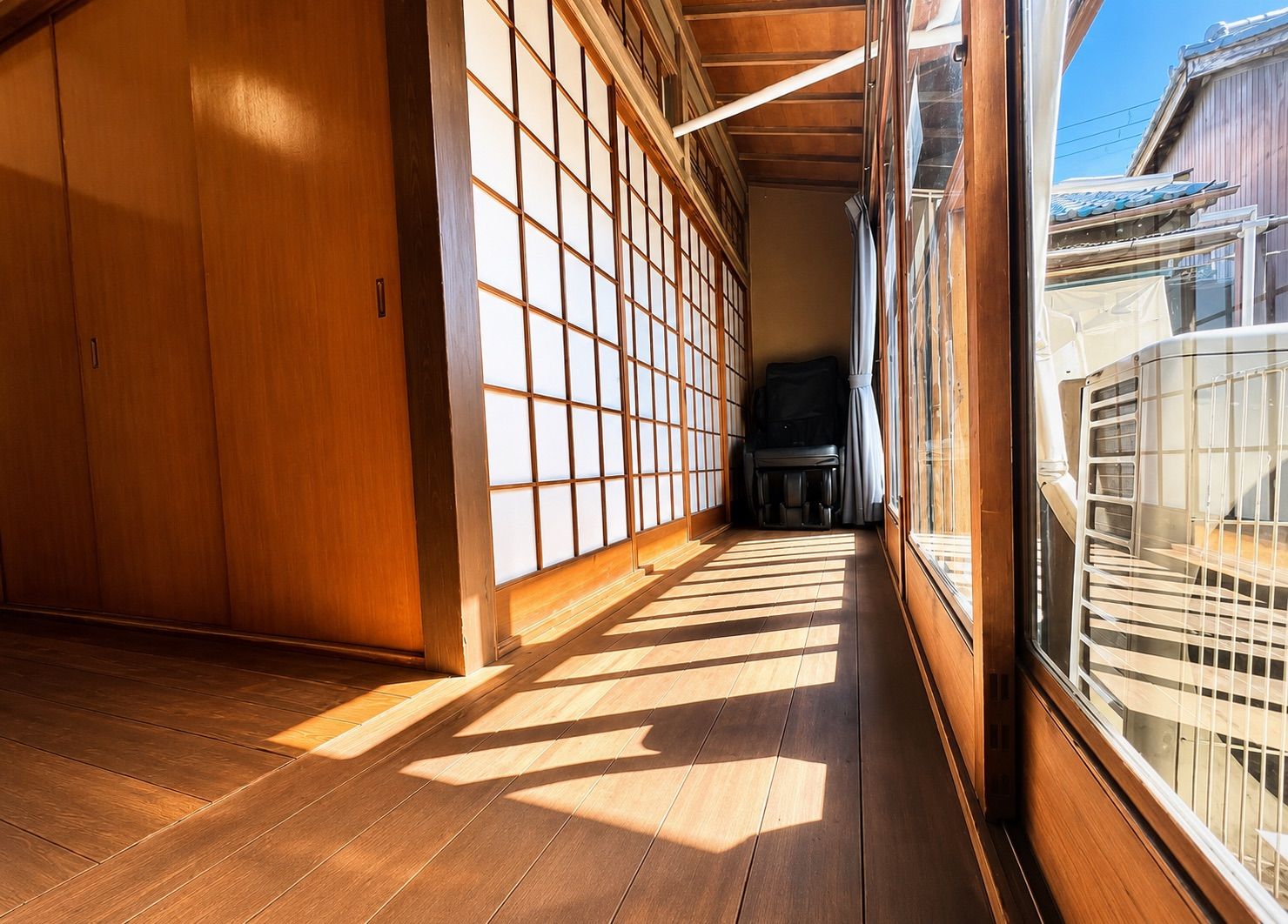 A traditional Japanese room with sliding doors, a tatami mat floor, and a view of traditional buildings outside.