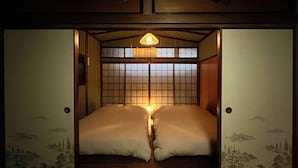 Una habitación tradicional japonesa con suelo de tatami, techo bajo y puertas correderas que dan a un paisaje montañoso.