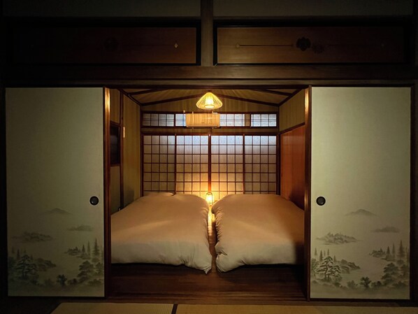 Ein traditioneller japanischer Raum mit Tatami-Böden, einer niedrigen Decke und Schiebetüren mit Blick auf eine gebirgige Landschaft.