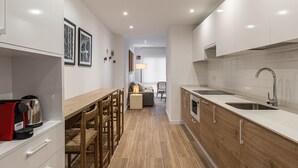 A modern kitchen with wooden cabinets, a stainless steel sink, and a coffee machine.