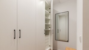 A walk-in closet with open shelves and a mirror.