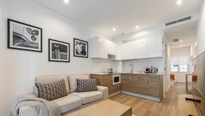 A modern apartment with a living area, kitchenette, and a small dining space.