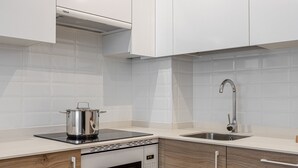 A modern kitchen with white cabinets, a stainless steel sink, and a built-in oven.
