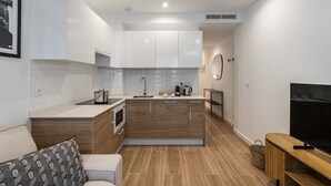 A modern kitchen with white cabinets, a built-in oven, and a coffee maker.