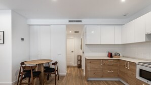A modern kitchen with white cabinets, a wooden dining table, and a built-in oven. - Waou Best IV Madrid Rio (Madrid)