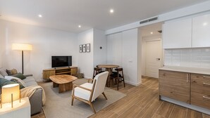 A modern living room with a flat-screen TV, a sofa, a coffee table, and a dining area with chairs. - Waou Best IV Madrid Rio (Madrid)